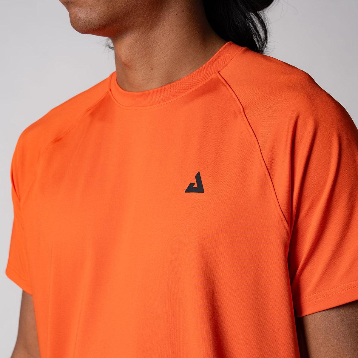 Nahaufnahme eines orangenen T-Shirts mit rundem Ausschnitt und kleinem schwarzem Logo auf der linken Brust.