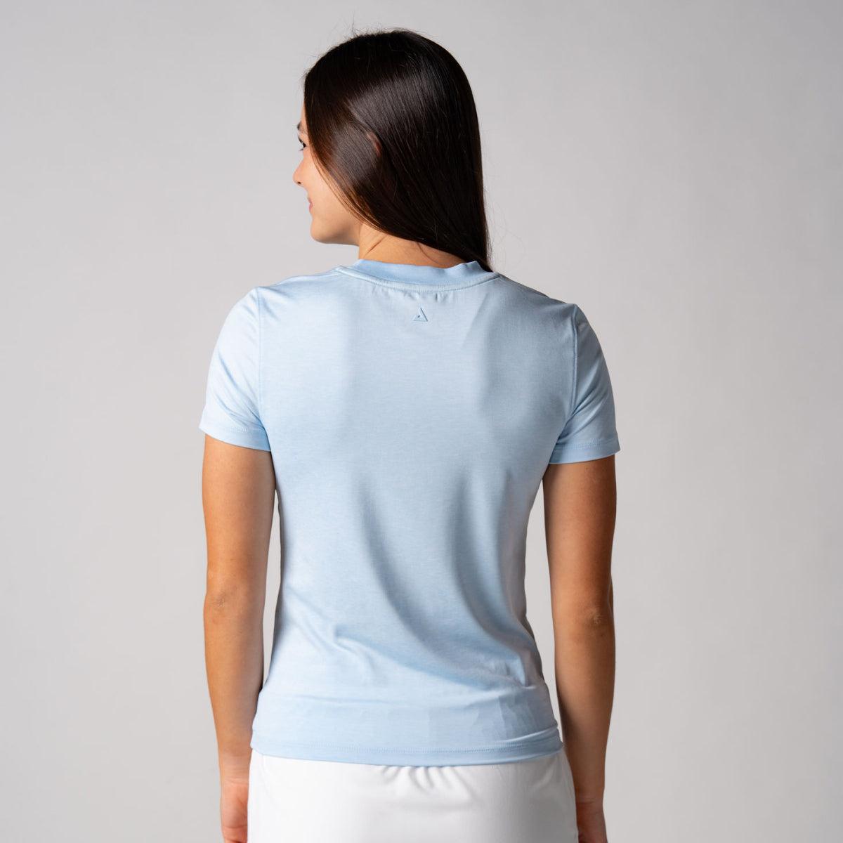 Frau von hinten trägt hellblaues, kurzärmeliges T-Shirt vor neutralem Hintergrund.