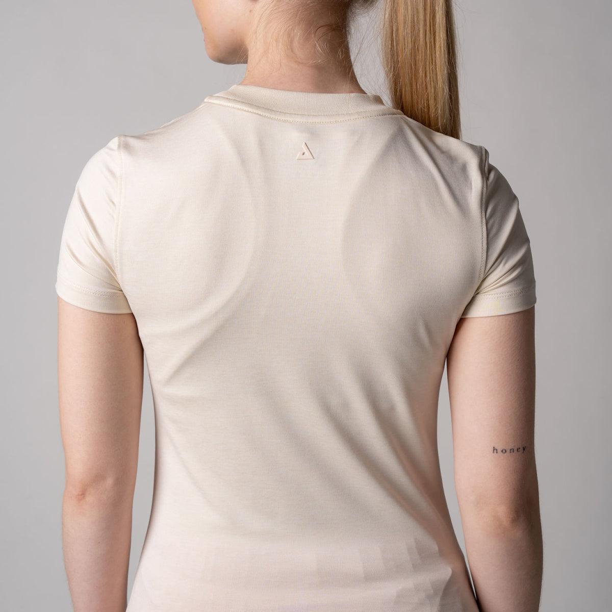 Frau trägt cremefarbenes, kurzärmeliges T-Shirt, Rückansicht.