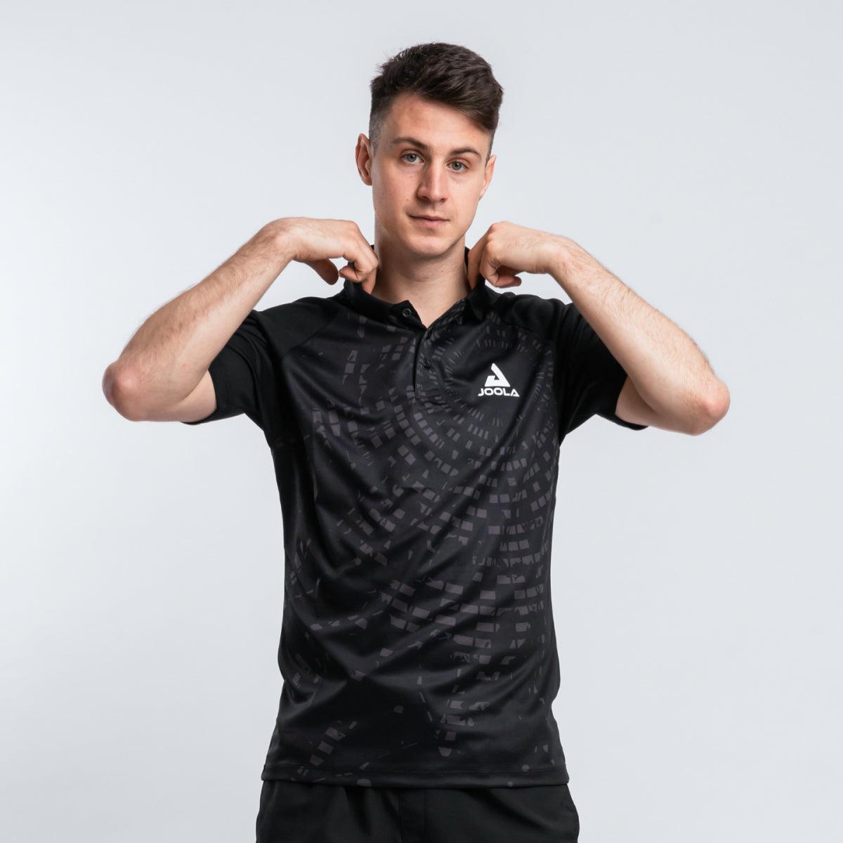Junger Mann trägt schwarzes JOOLA Polo-Shirt mit dezentem Muster.