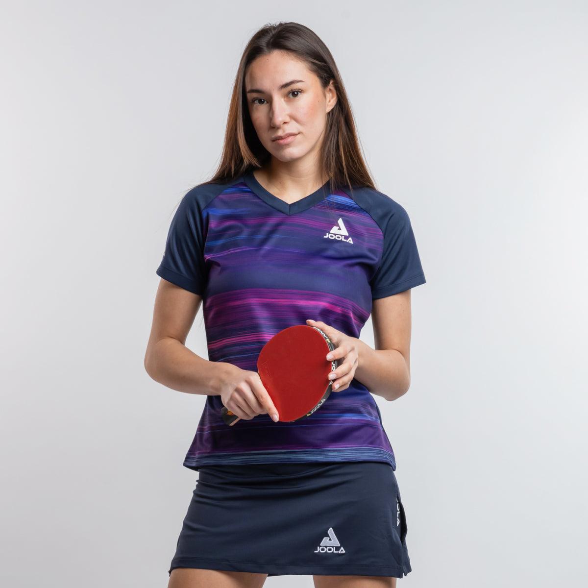 Frau in blau-lila JOOLA Tischtennis-Sportoutfit hält roten Tischtennisschläger.