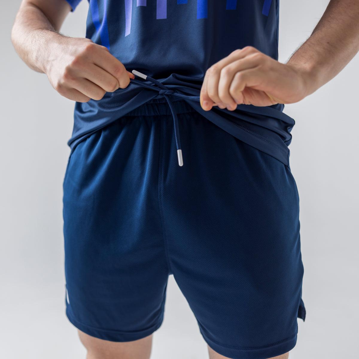 Mann bindet Kordel einer dunkelblauen Sportshorts mit elastischem Bund.