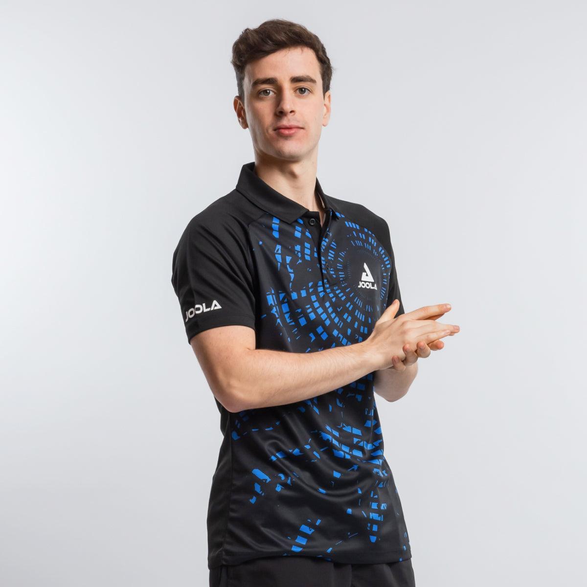 Mann trägt schwarzes JOOLA-Poloshirt mit blauem, pixelartigem Muster.
