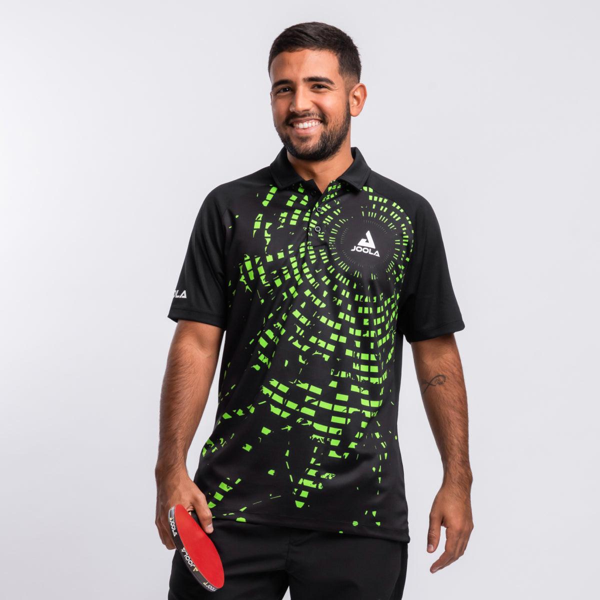 Mann trägt schwarzes JOOLA-Poloshirt mit grünem, pixelartigem Muster und hält roten Tischtennisschläger.
