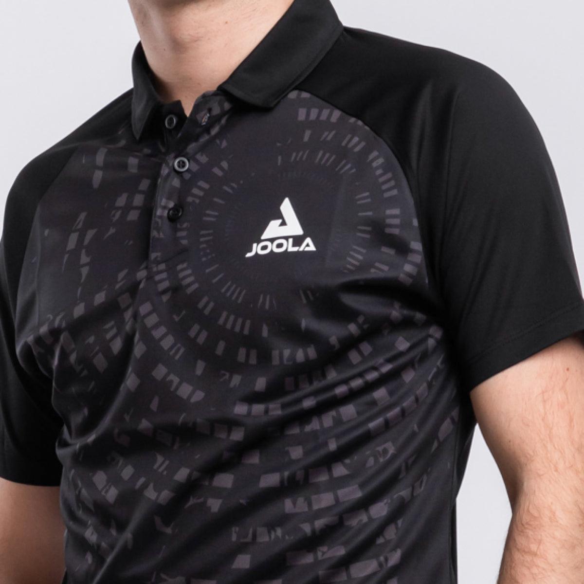 Schwarzes JOOLA Polo-Shirt mit kurzem Arm und grafischem Muster, getragen von einer Person.