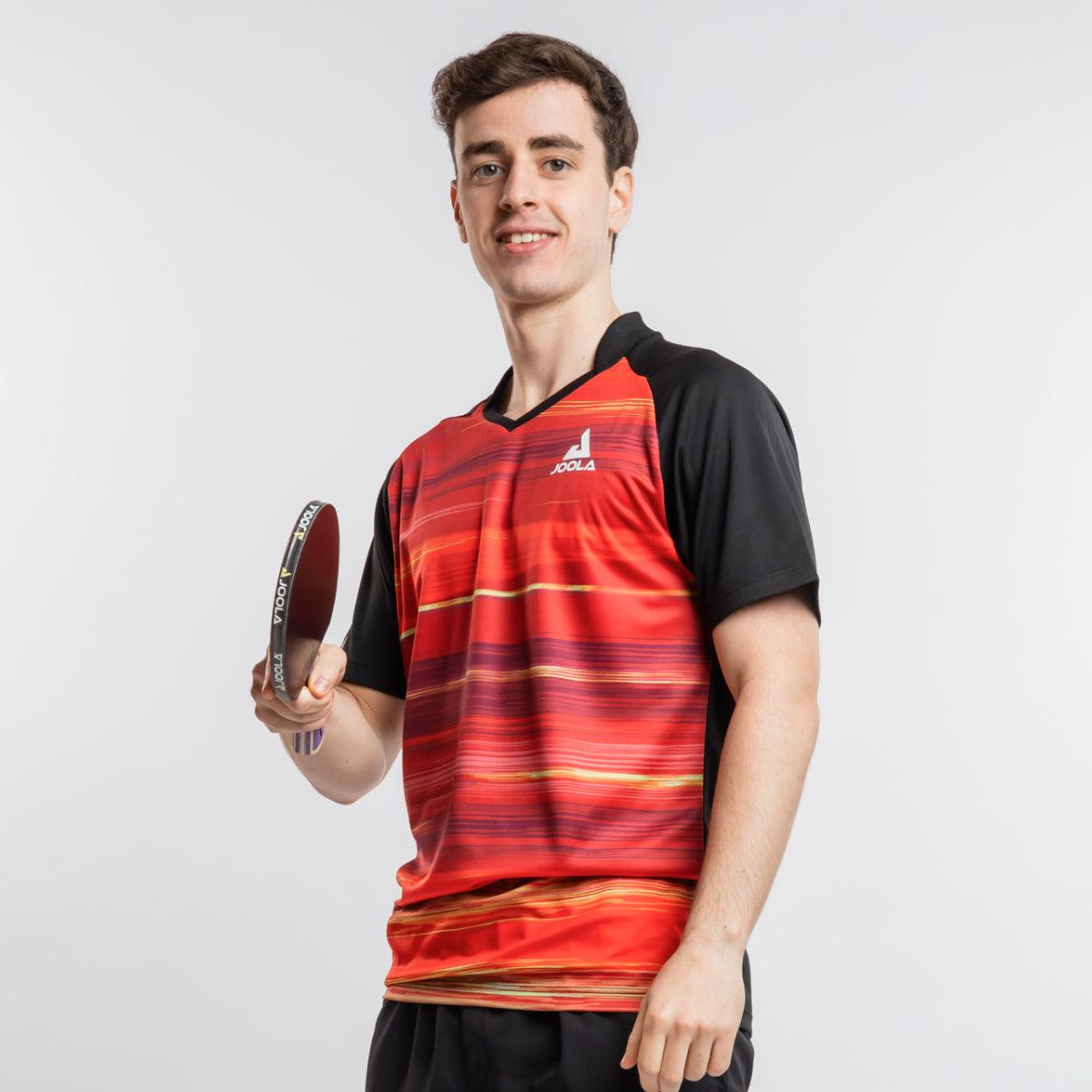 Junger Mann in rotem und schwarzem JOOLA Tischtennis-Trikot hält Tischtennisschläger.